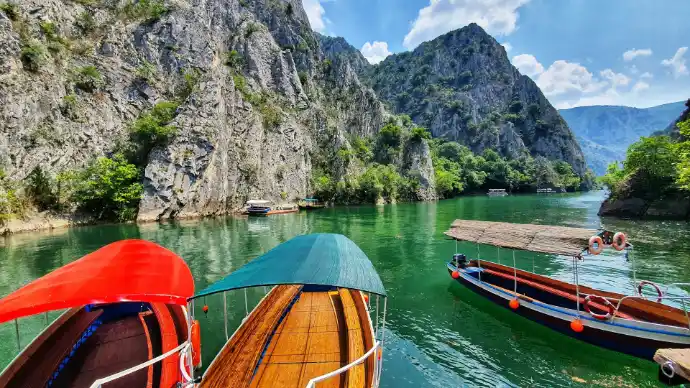 brown wooden boat on body of water near mountain during daytime